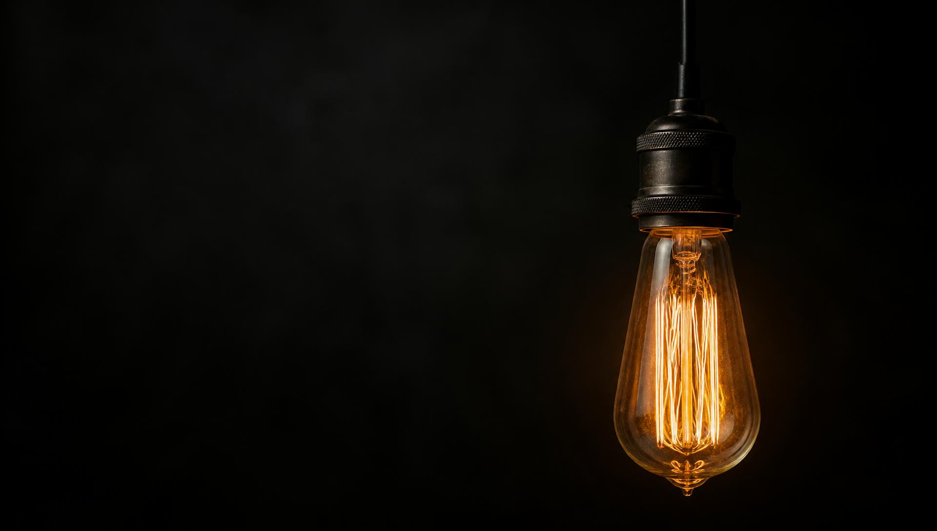A vintage filament bulb glowing in a dark room